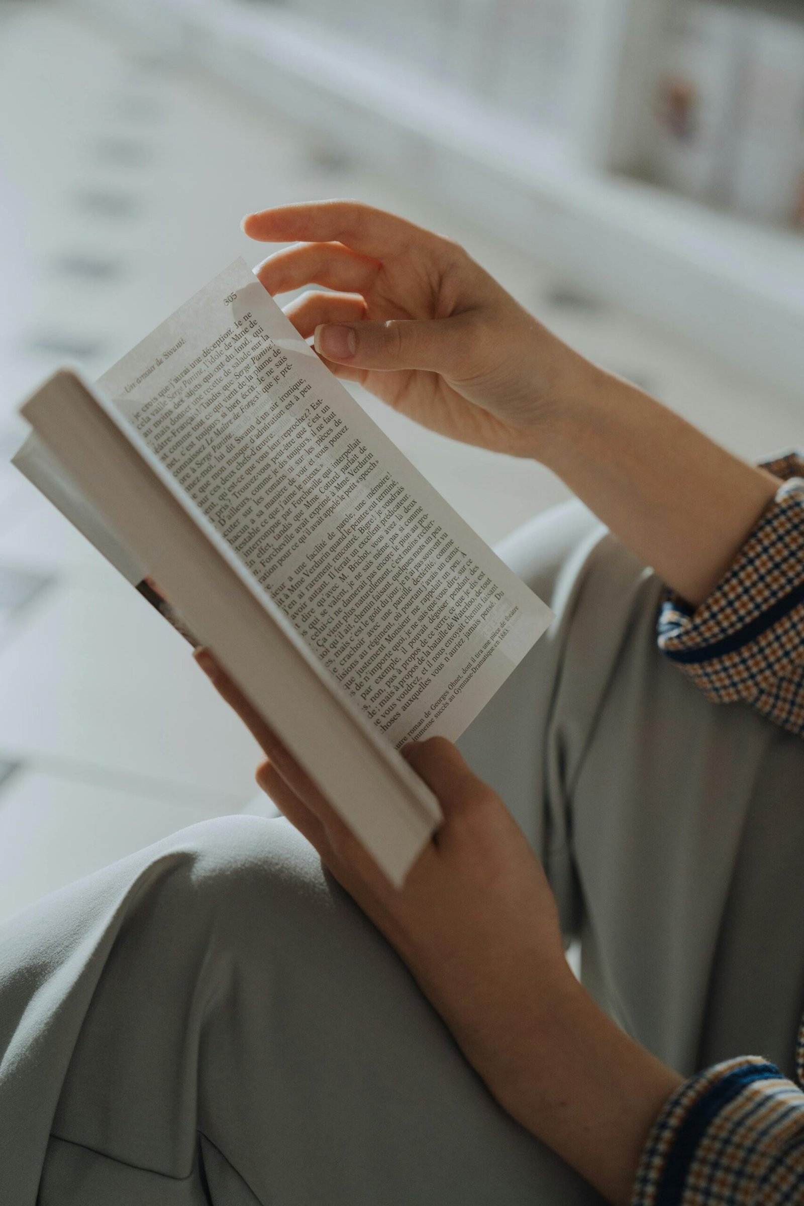 Close-up shot of hands holding an open book indoors with a soft focus background.